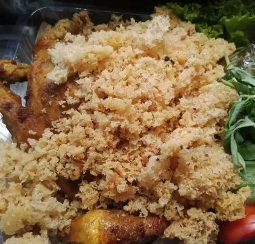 Ayam kampung goreng tertutup kremesan tebal di atas daun selada