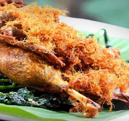 Bebek goreng laos bertabur kremesan di atas daun pisang
