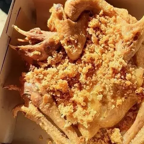 Ingkung ayam goreng kremes utuh di dalam kemasan kertas