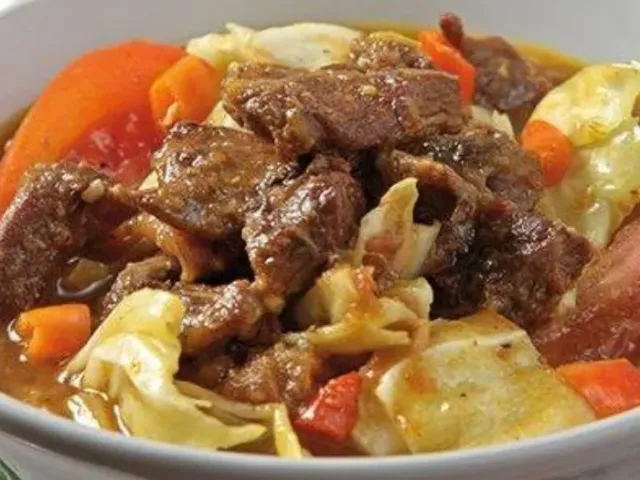 Tongseng kambing berkuah kemerahan dengan potongan kol dan tomat